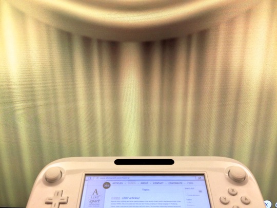 A photo of the gamepad being used, with curtains on the TV screen hiding the site